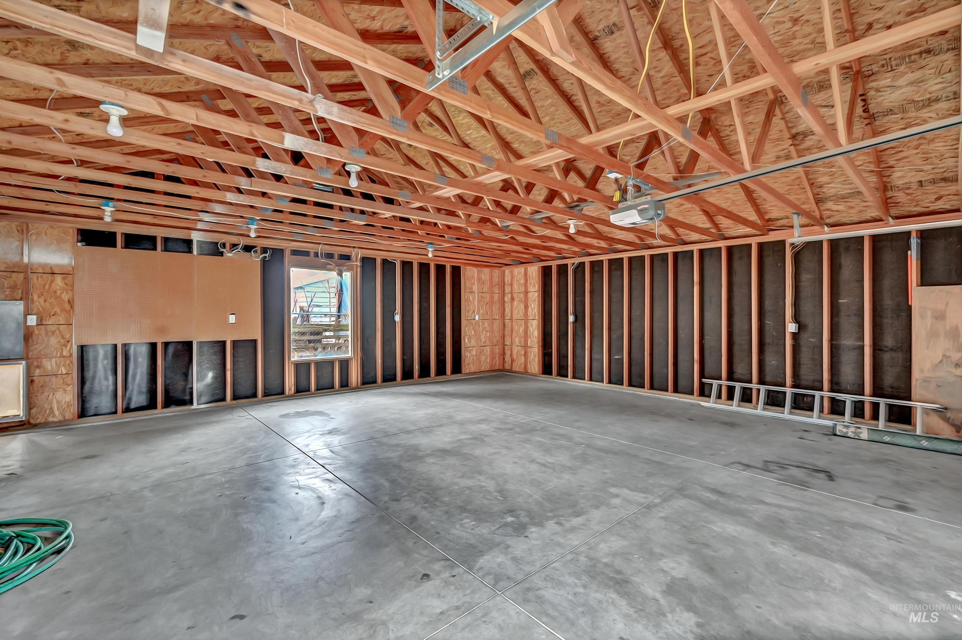 Oversized two-car garage with concrete floor and ample space for vehicles and storage/tools/toys.