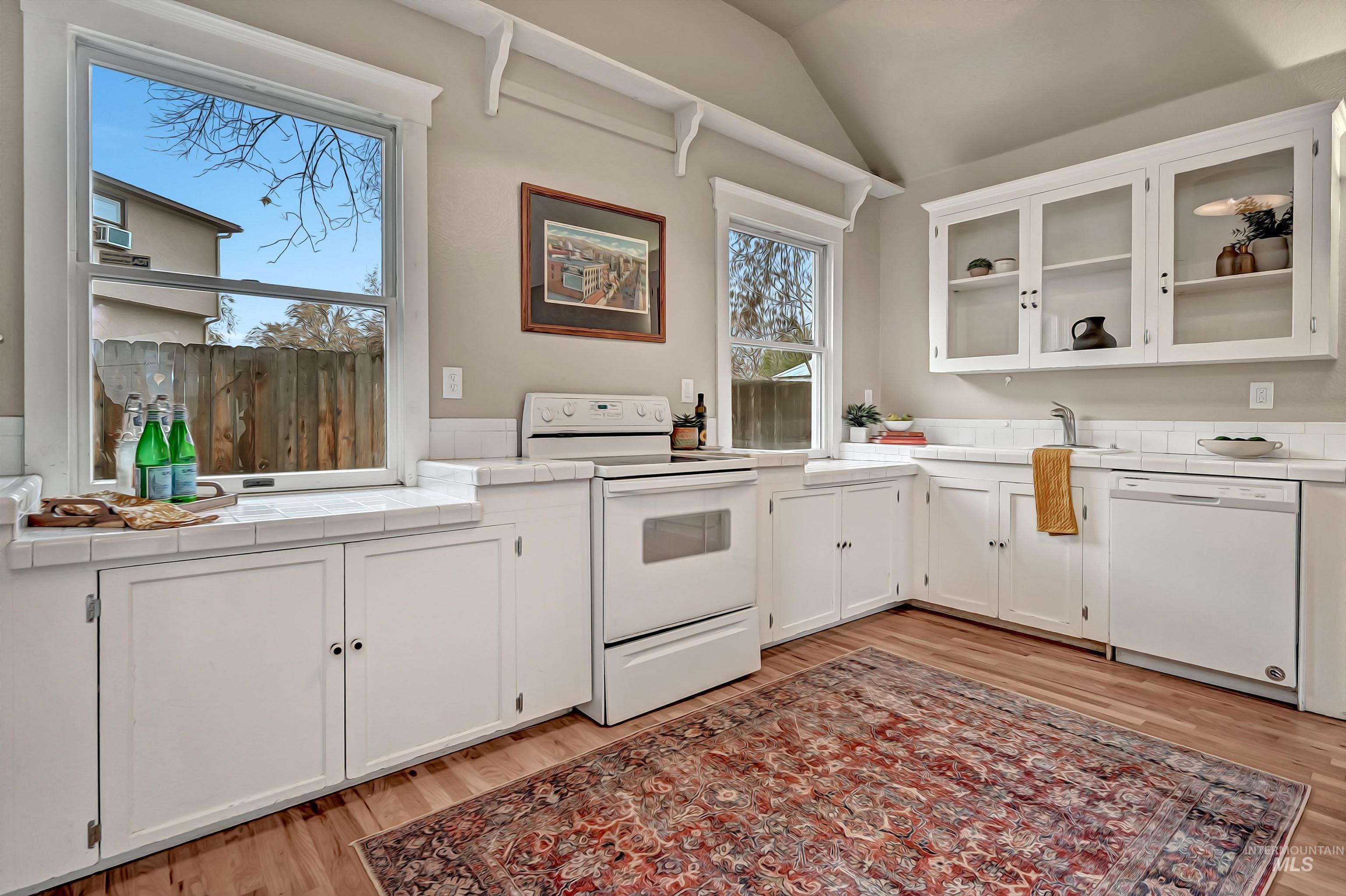 Open, light-filled kitchen with glass-front cabinets and large windows that bring in great natural light.