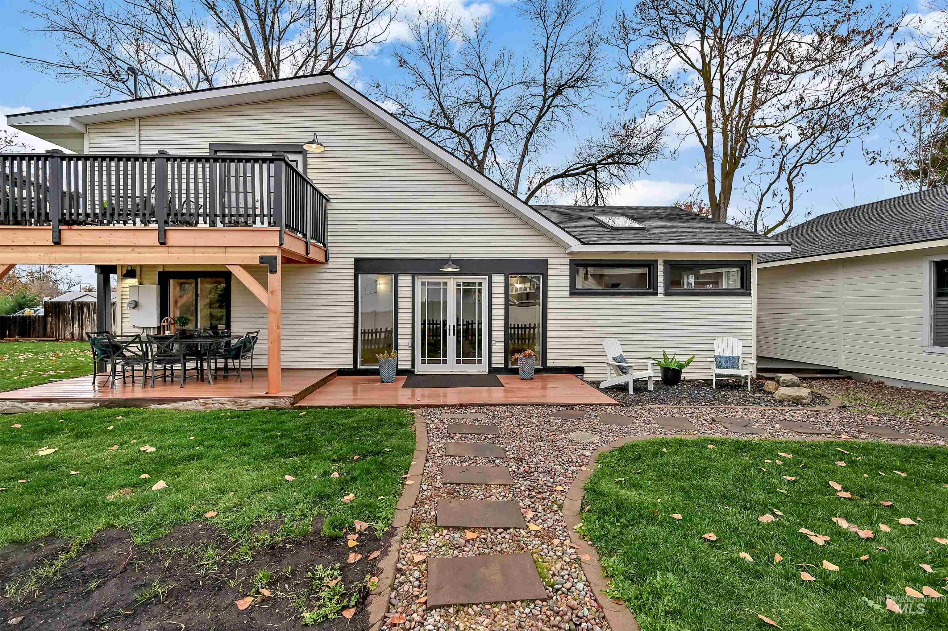 Crisp, updated exterior with French doors opening to a spacious patio, private seating area, and an elevated deck above. A stone walkway, large windows for natural light, and clean curb appeal. Great indoor?outdoor flow for entertaining.