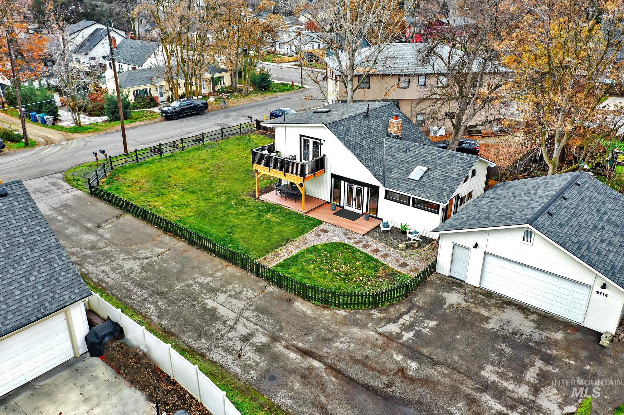 Aerial shot displaying the convenient layout with fenced yard, detached two-car garage, and easy access to both levels of the home from the deck and patio areas.