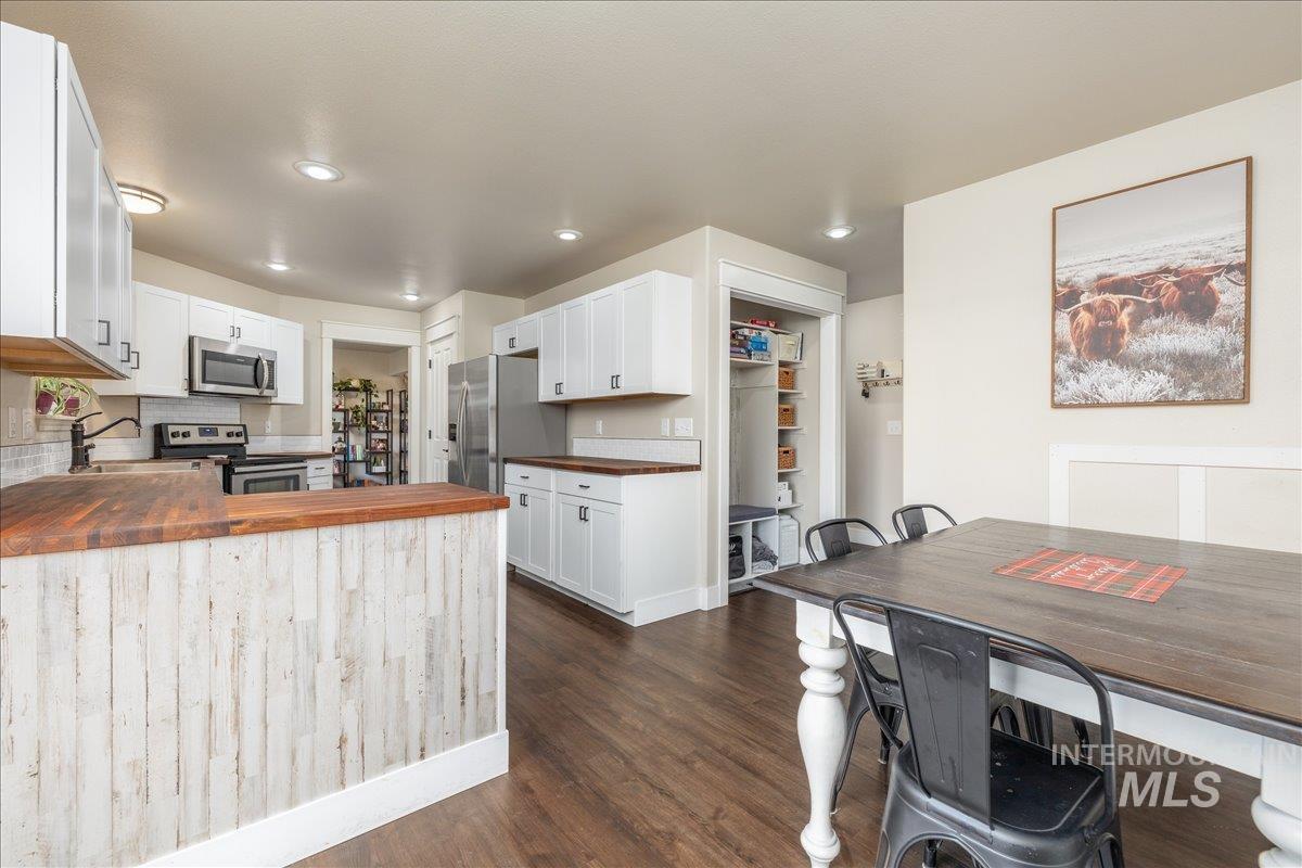 Kitchen featuring wooden counters, stainless steel appliances, white cabinets, a peninsula, and recessed lighting