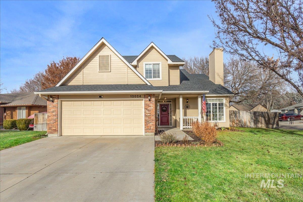 Traditional-style home with covered porch, a chimney, concrete driveway, roof with shingles, and brick siding