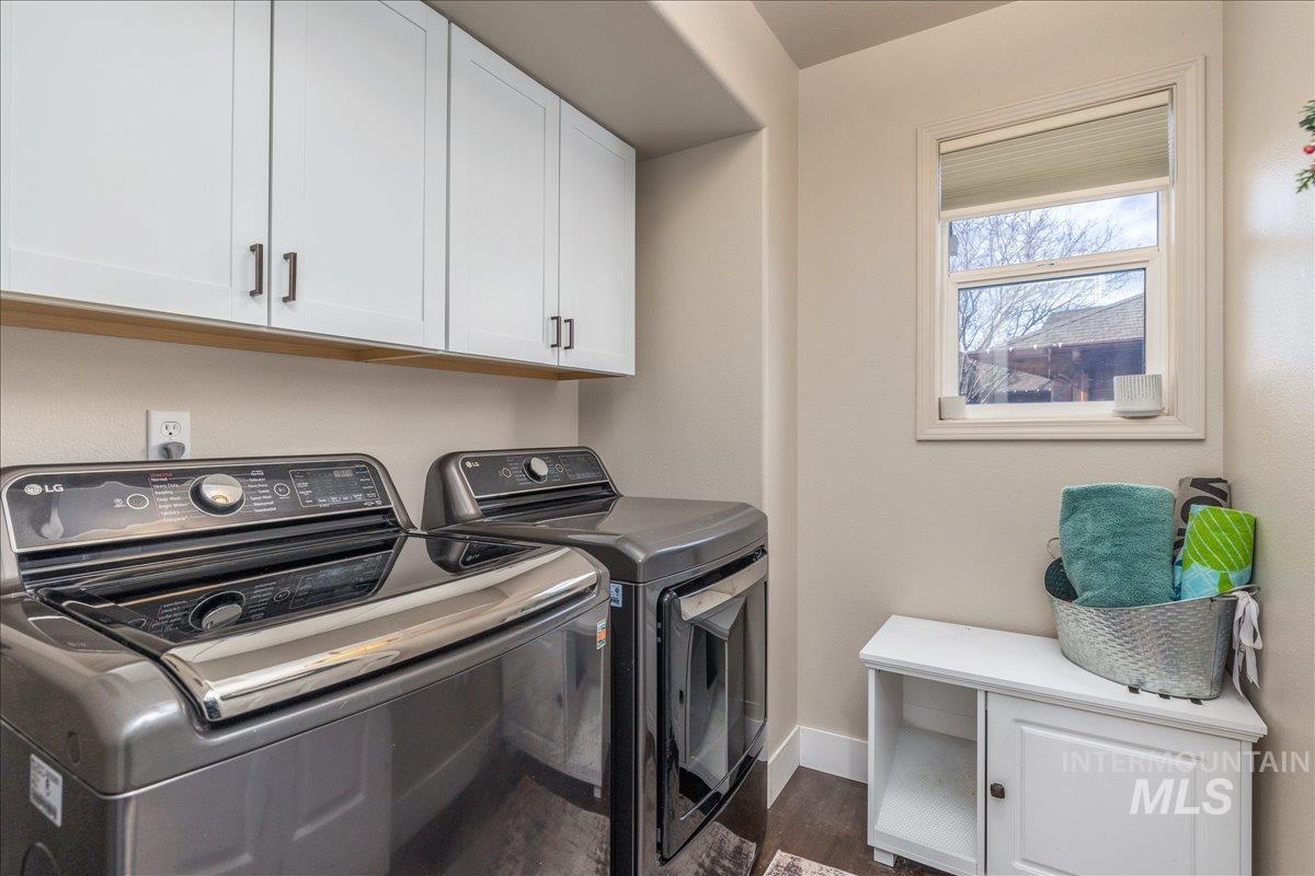 Laundry room featuring cabinet space, washing machine and clothes dryer, and dark wood-style flooring