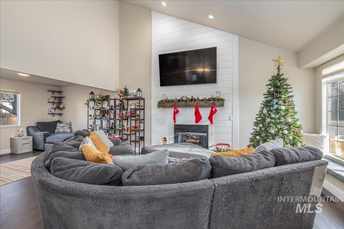 Living area featuring healthy amount of natural light, wood finished floors, lofted ceiling, a large fireplace, and recessed lighting