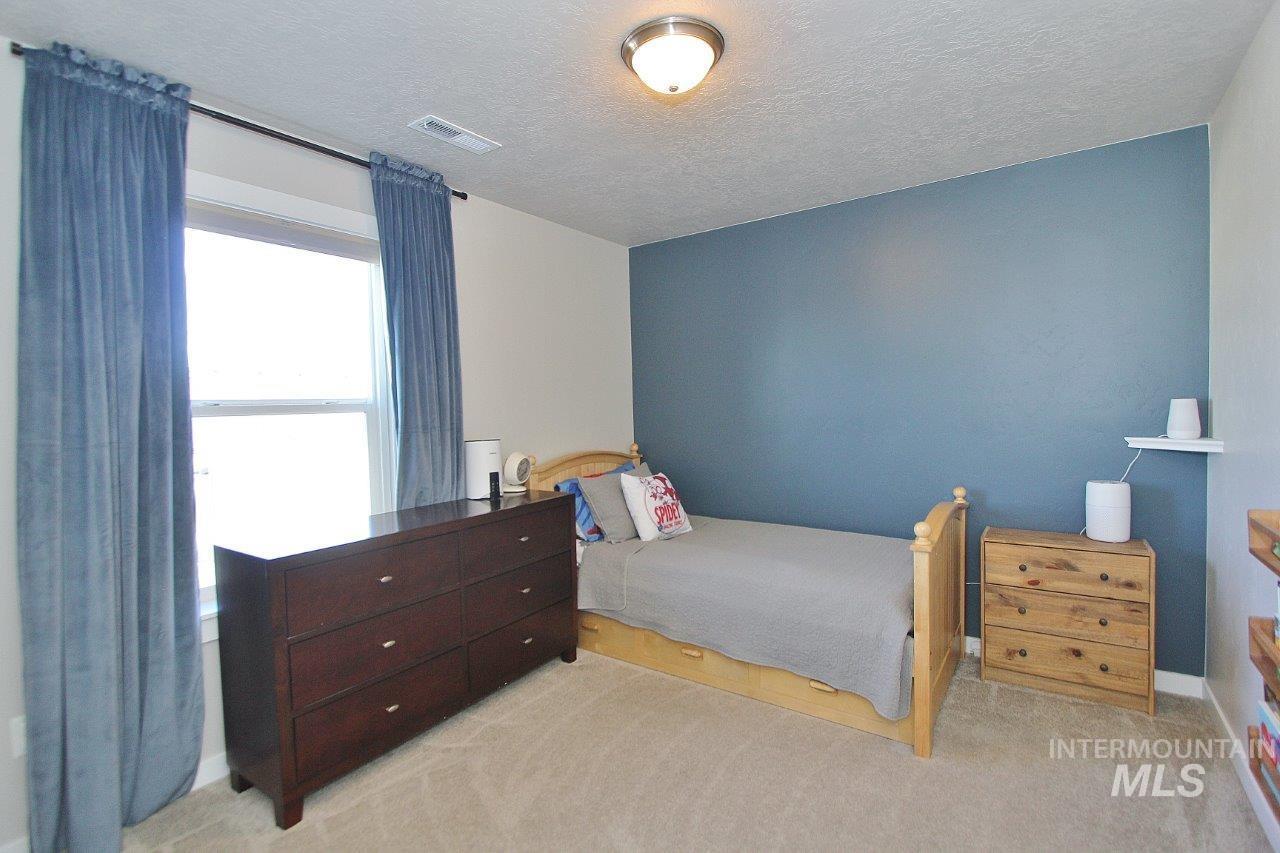 Bedroom featuring light colored carpet and a textured ceiling