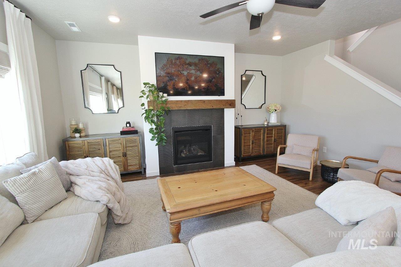 Living area featuring a tiled fireplace, wood finished floors, a textured ceiling, and a ceiling fan