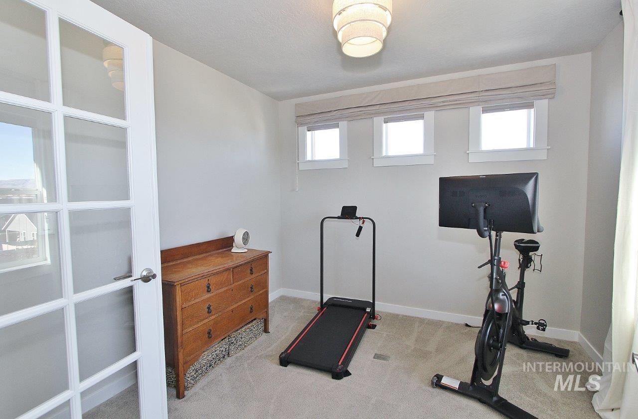 Workout area featuring light colored carpet and baseboards