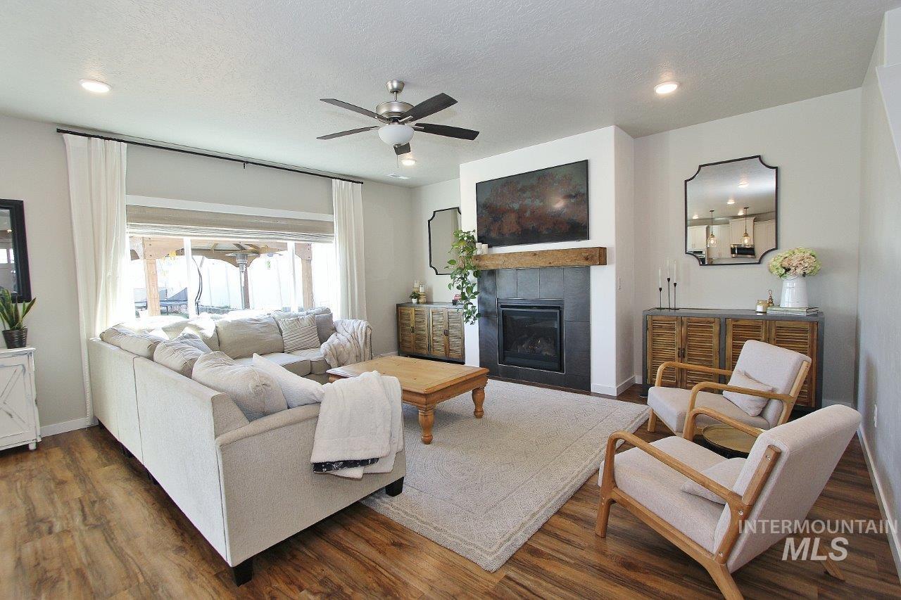 Living room featuring a tile fireplace, a ceiling fan, wood finished floors, a textured ceiling, and recessed lighting