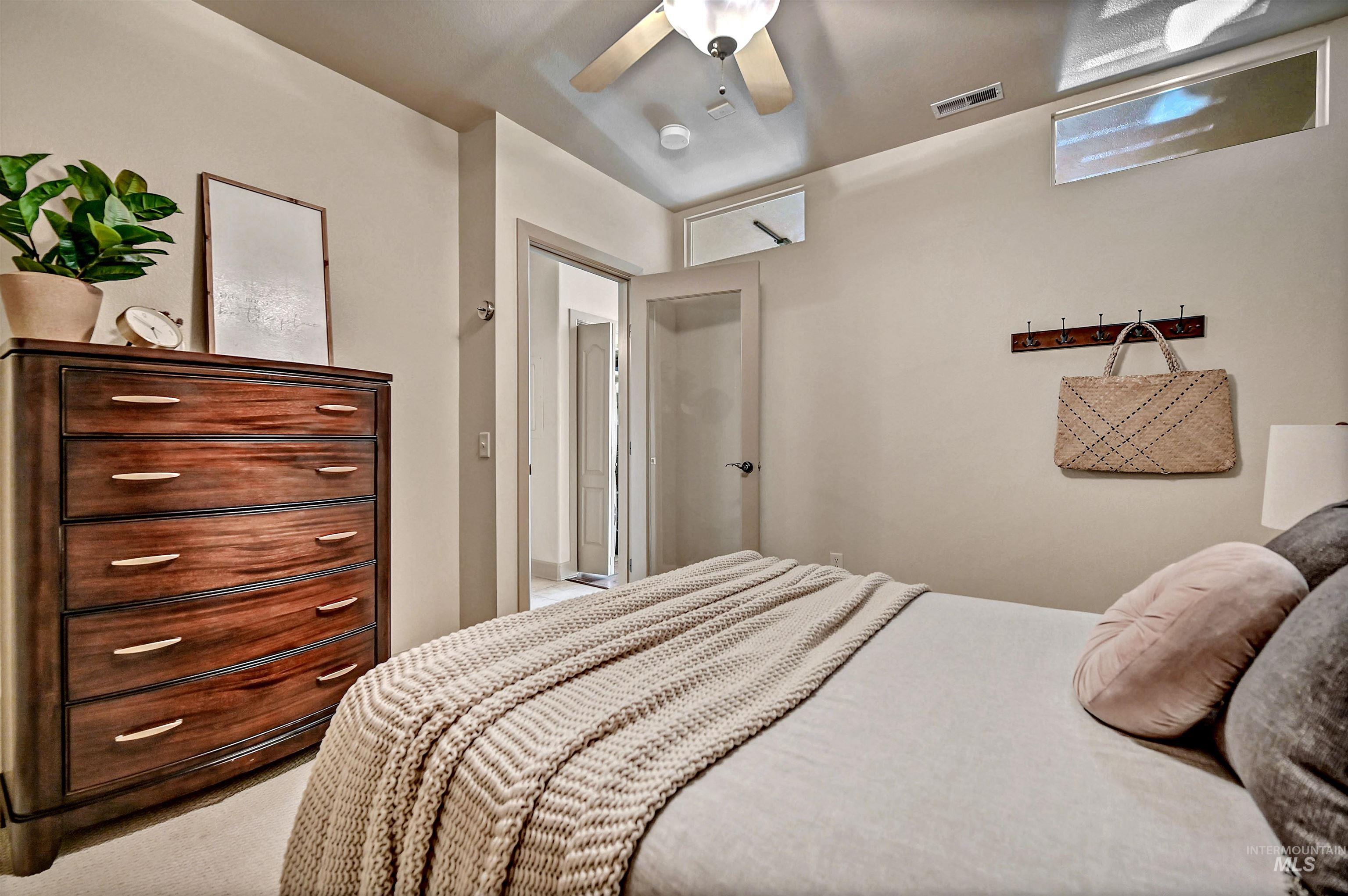 Bedroom with a large wall-to-wall wardrobe closet, ceiling fan and carpet flooring