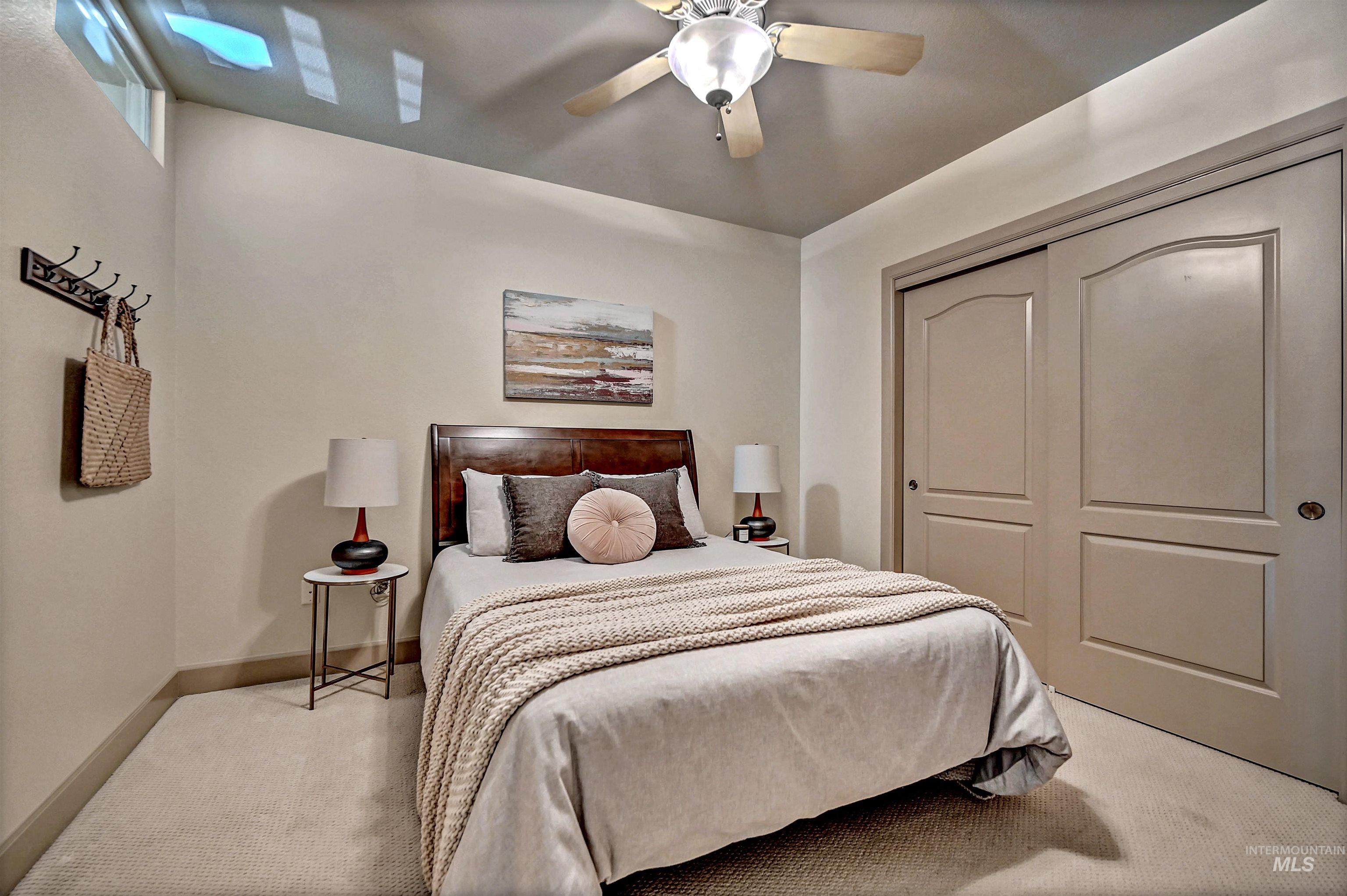 Carpeted bedroom featuring large wall-to-wall wardrobe closet, ceiling fan and a closet