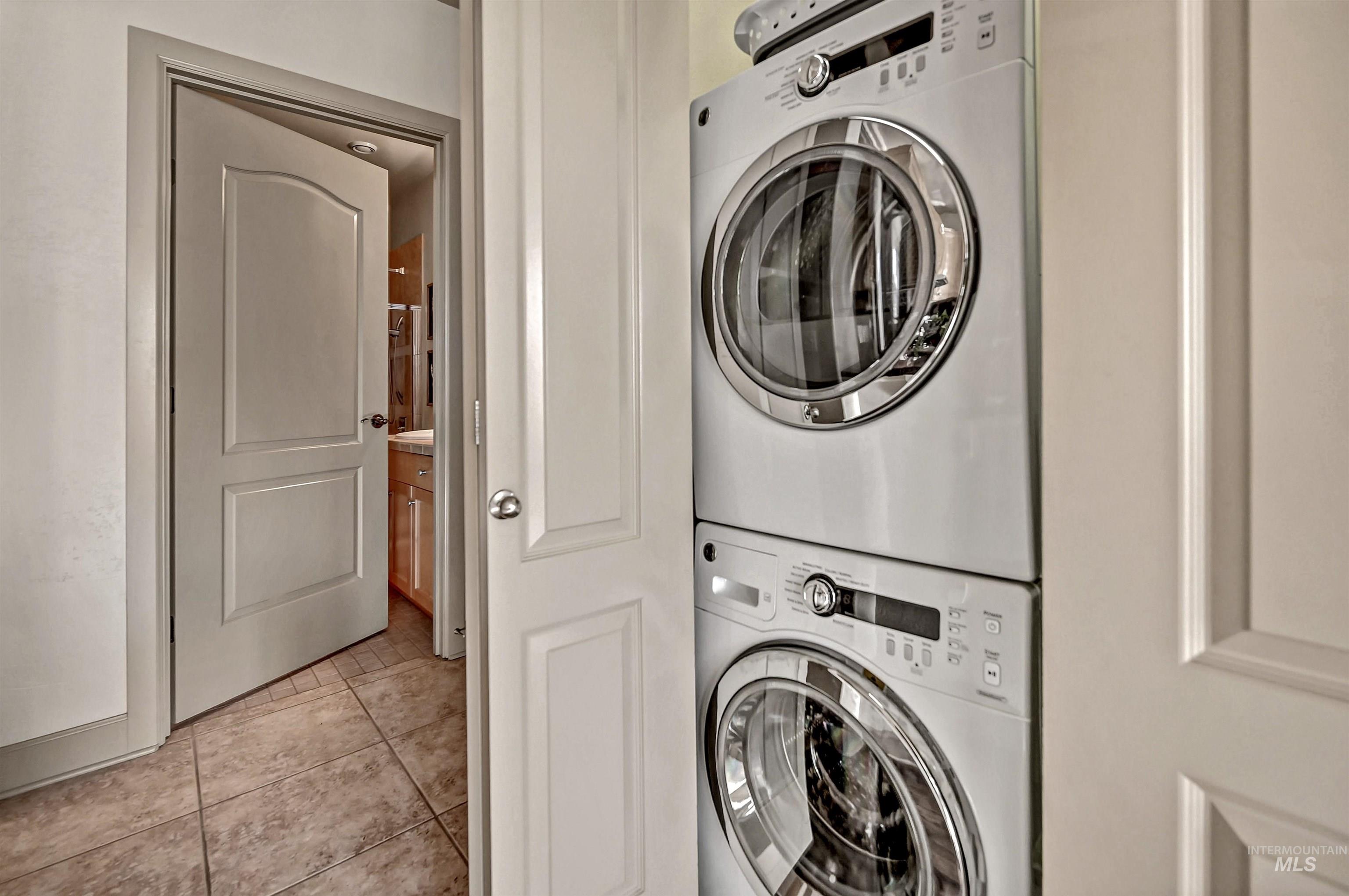 In-unit laundry area featuring stacked washer/dryer and storage closet.