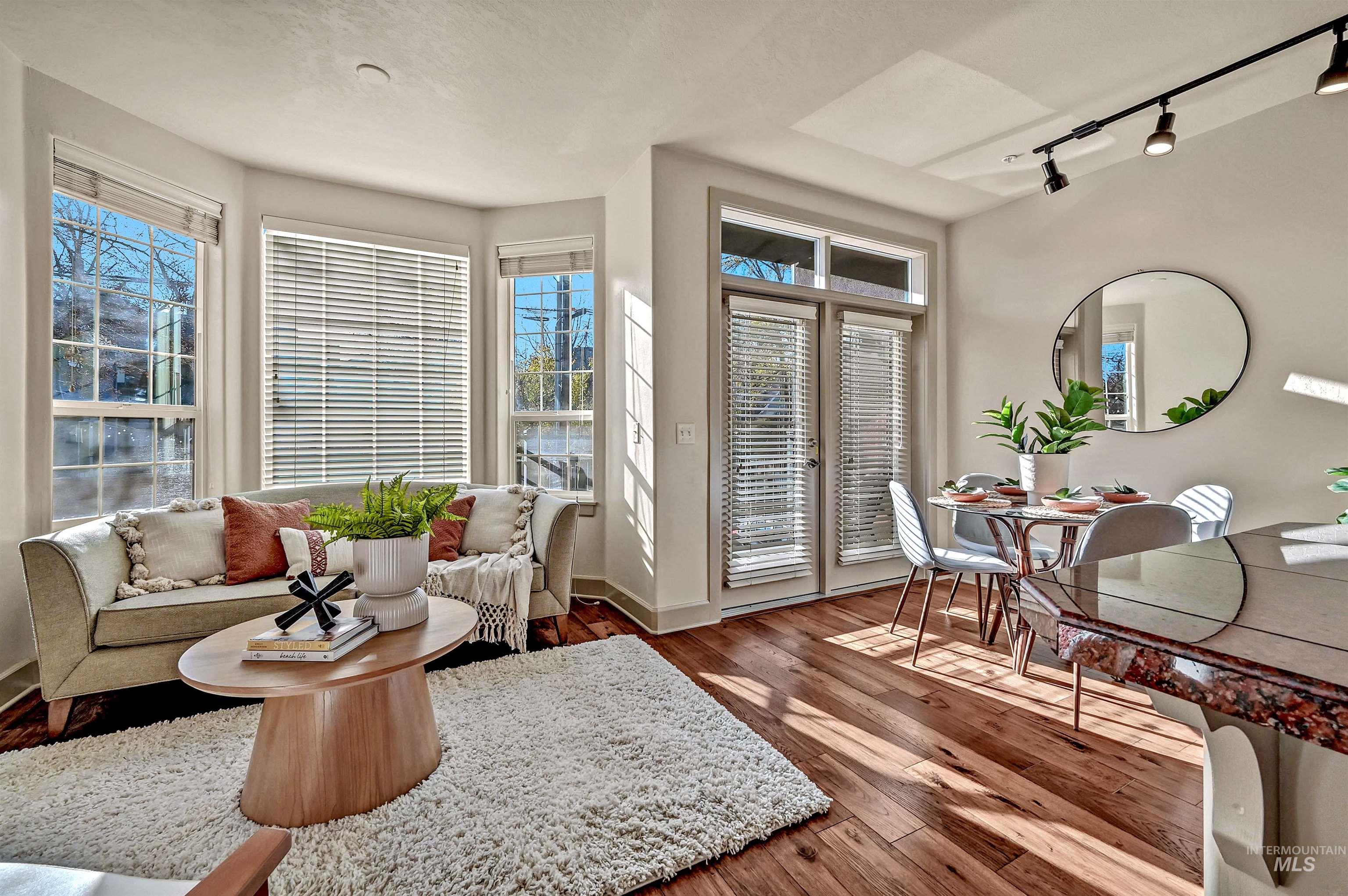 Living area with hardwood flooring and south facing walls of glass for a sunny interior.