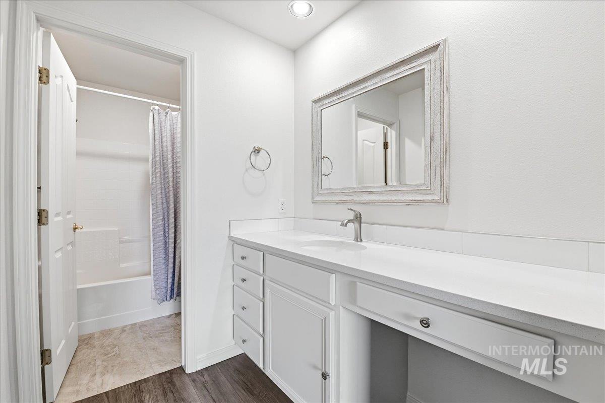 Bathroom featuring a single-sink vanity with white cabinetry, a built-in makeup area, a framed mirror, and recessed lighting