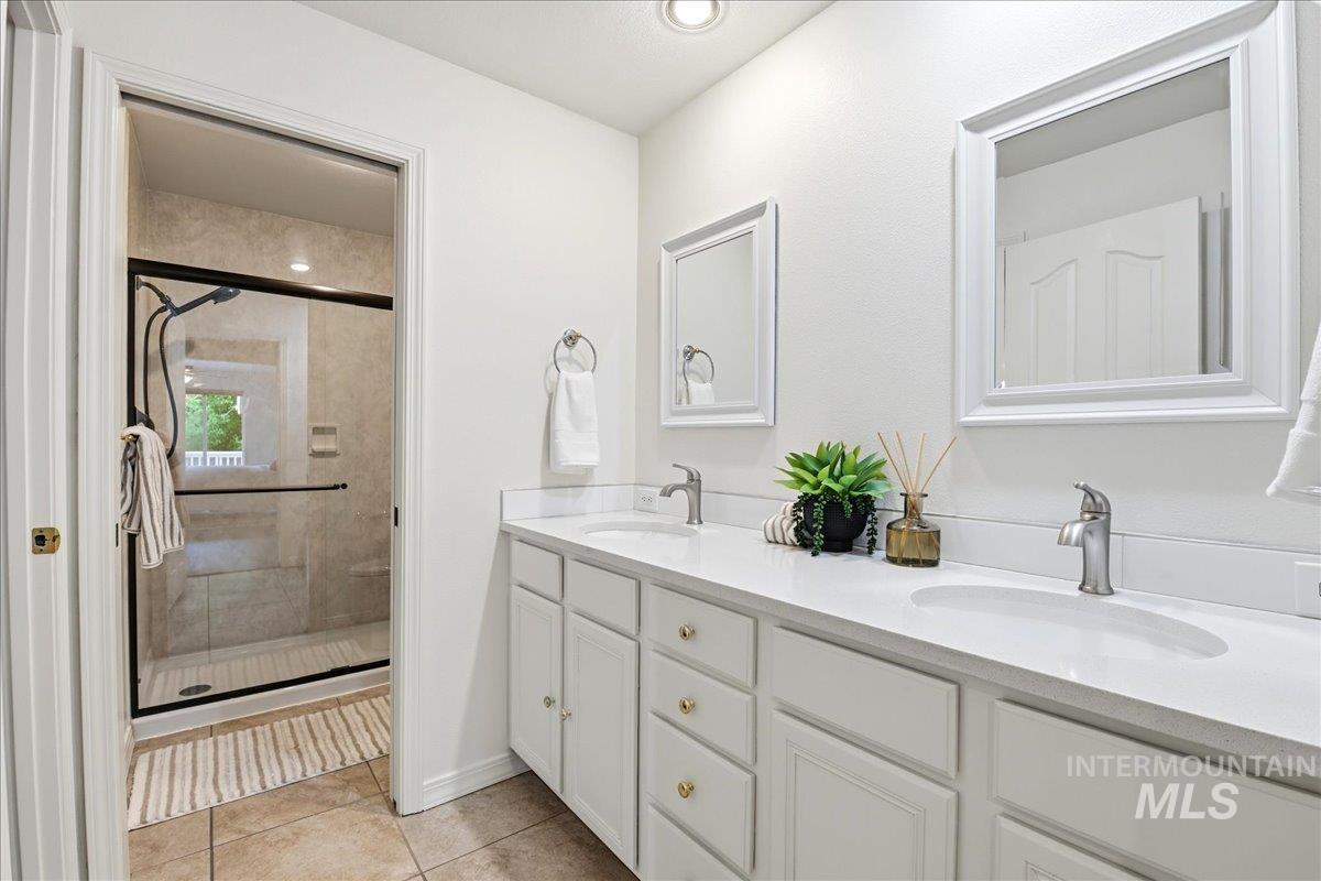 Bathroom featuring a dual vanity with white cabinetry and integrated sinks, complemented by framed mirrors
