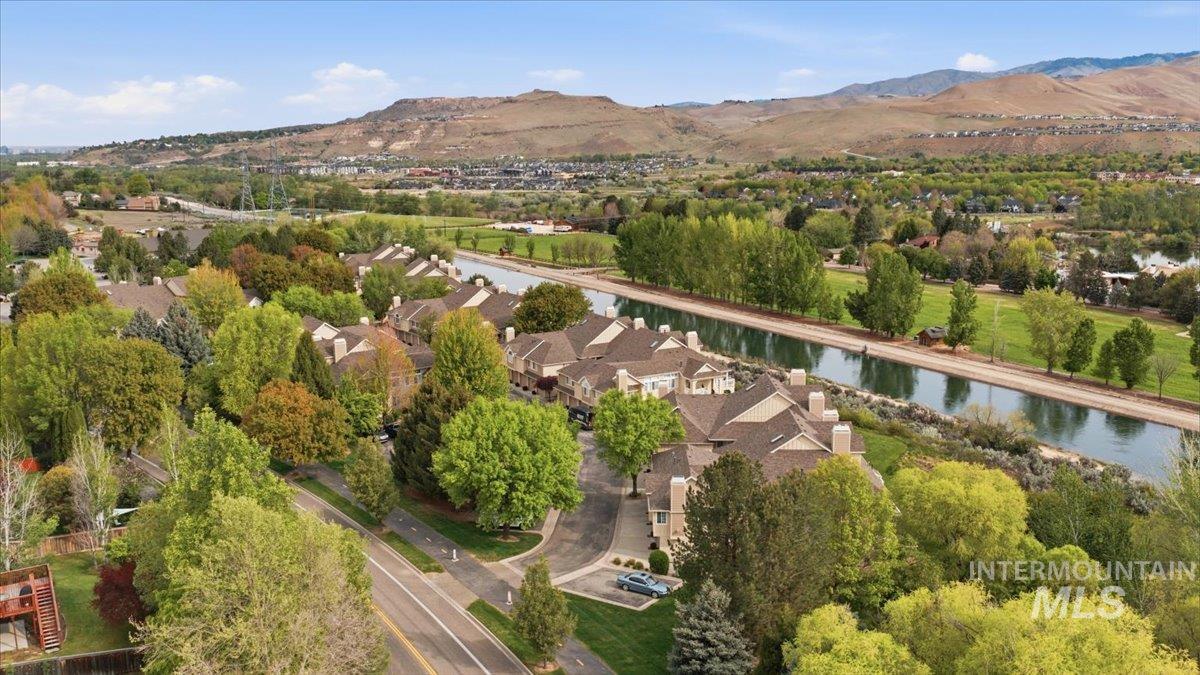 Aerial perspective showcasing a residential community bordered by a waterway and green spaces, with distant mountains providing a scenic backdrop