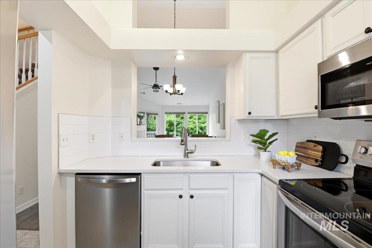 Modern kitchen featuring white cabinetry, stainless steel appliances, a white subway tile backsplash, and light-toned countertops