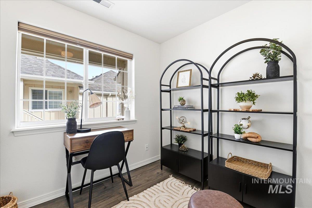 Interior room featuring wood-finish flooring, white walls, and a large window with grid panes