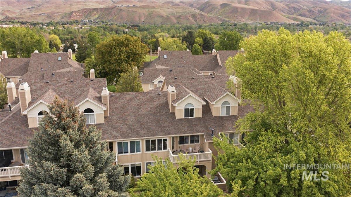Multi-level structure featuring a composite shingle roof, dormer windows, and light-toned exterior siding