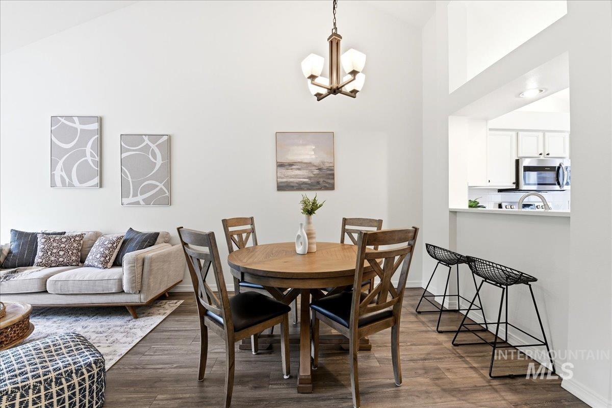 Open-concept living space featuring vaulted ceilings, wood-finish flooring, and a kitchen pass-through with a breakfast bar