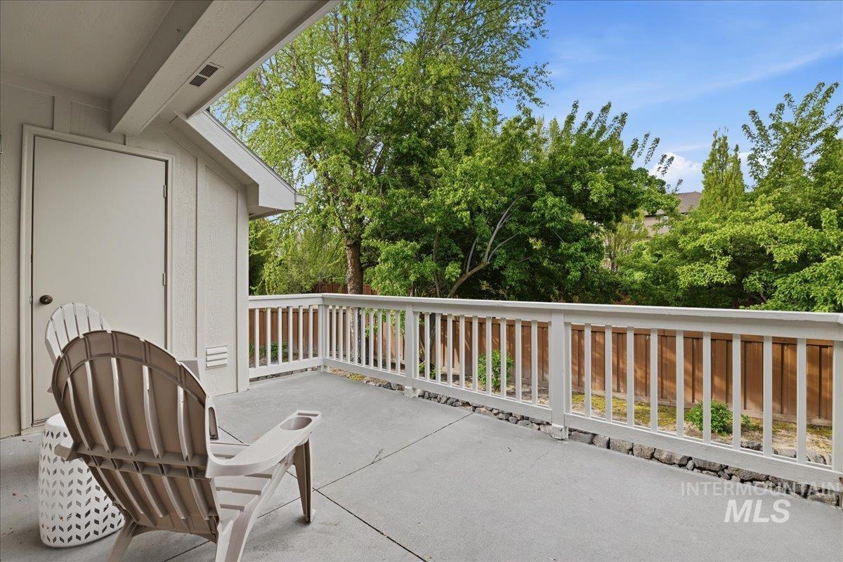 Outdoor deck space with concrete flooring, white painted railing, and a solid exterior door