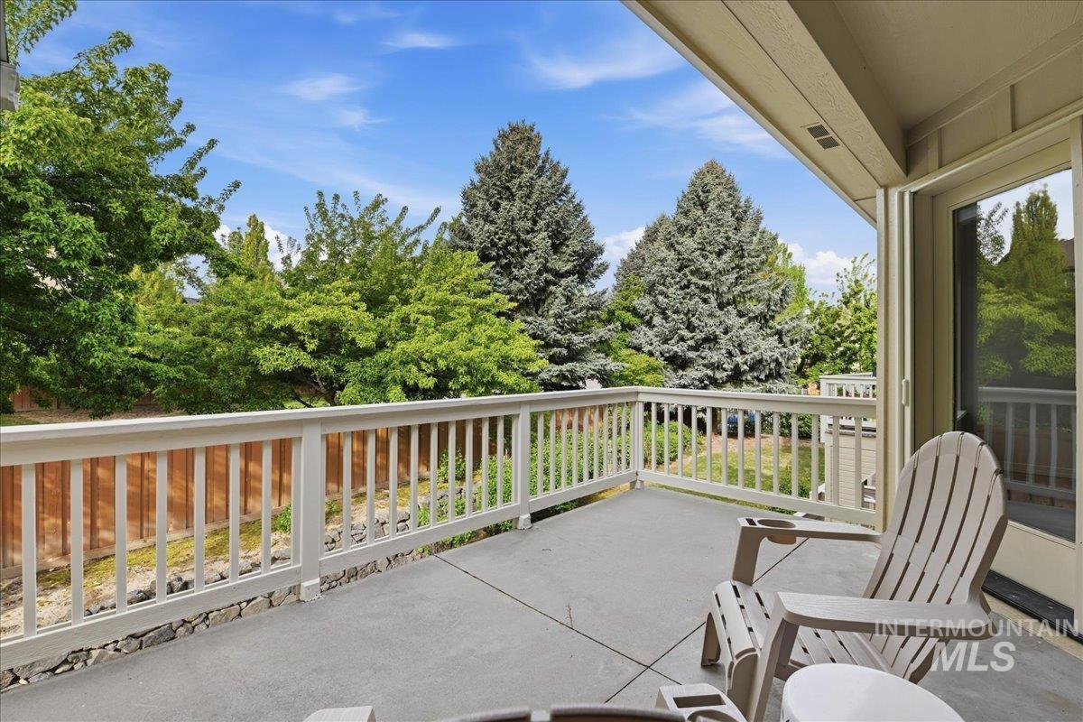 Spacious outdoor patio featuring a concrete surface, white railing, and sliding glass door access