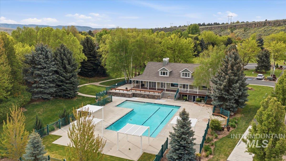 Outdoor swimming pool with integrated lap lanes surrounded by a concrete deck, shaded pergolas, and a perimeter fence