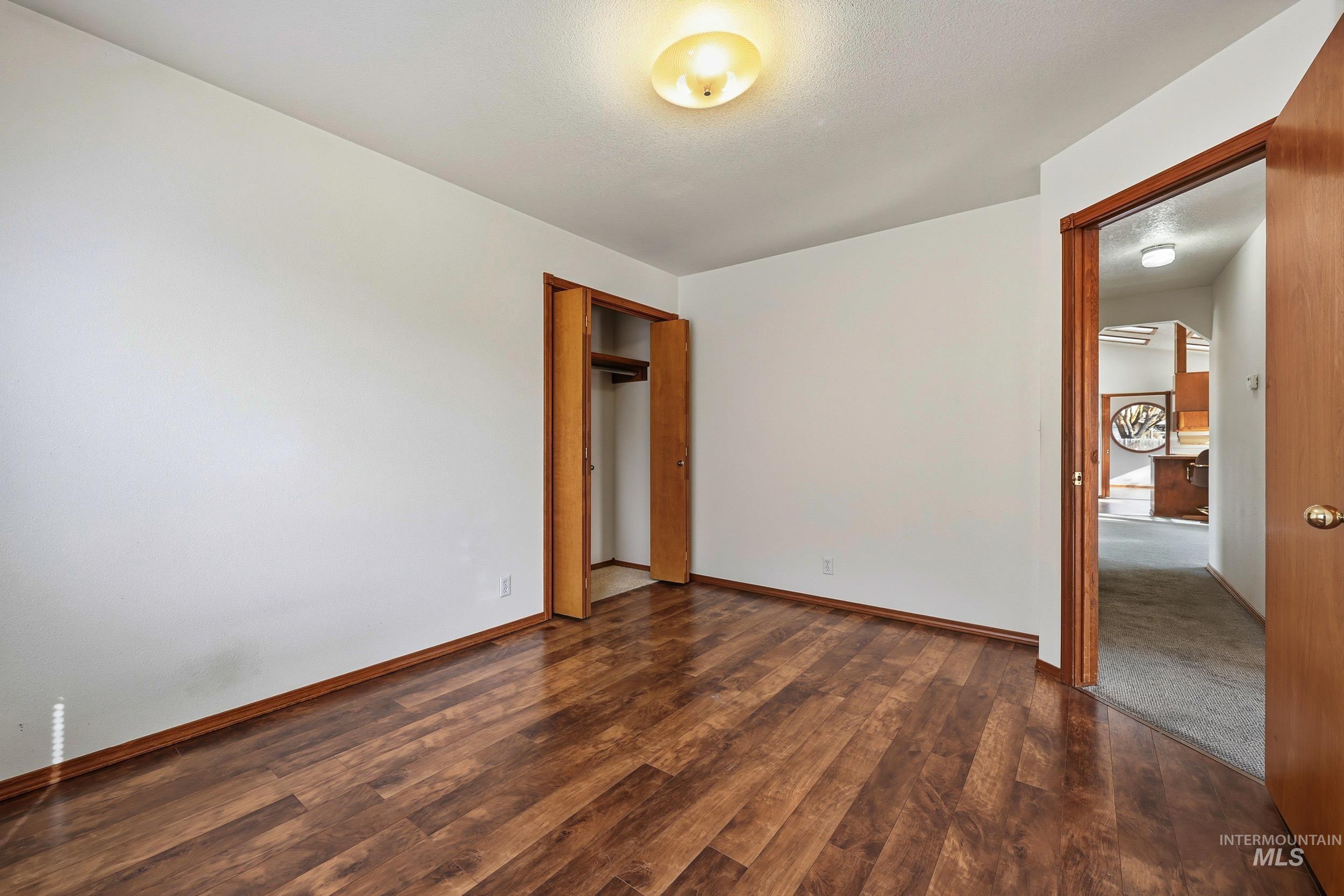 Unfurnished bedroom with dark wood finished floors and a closet