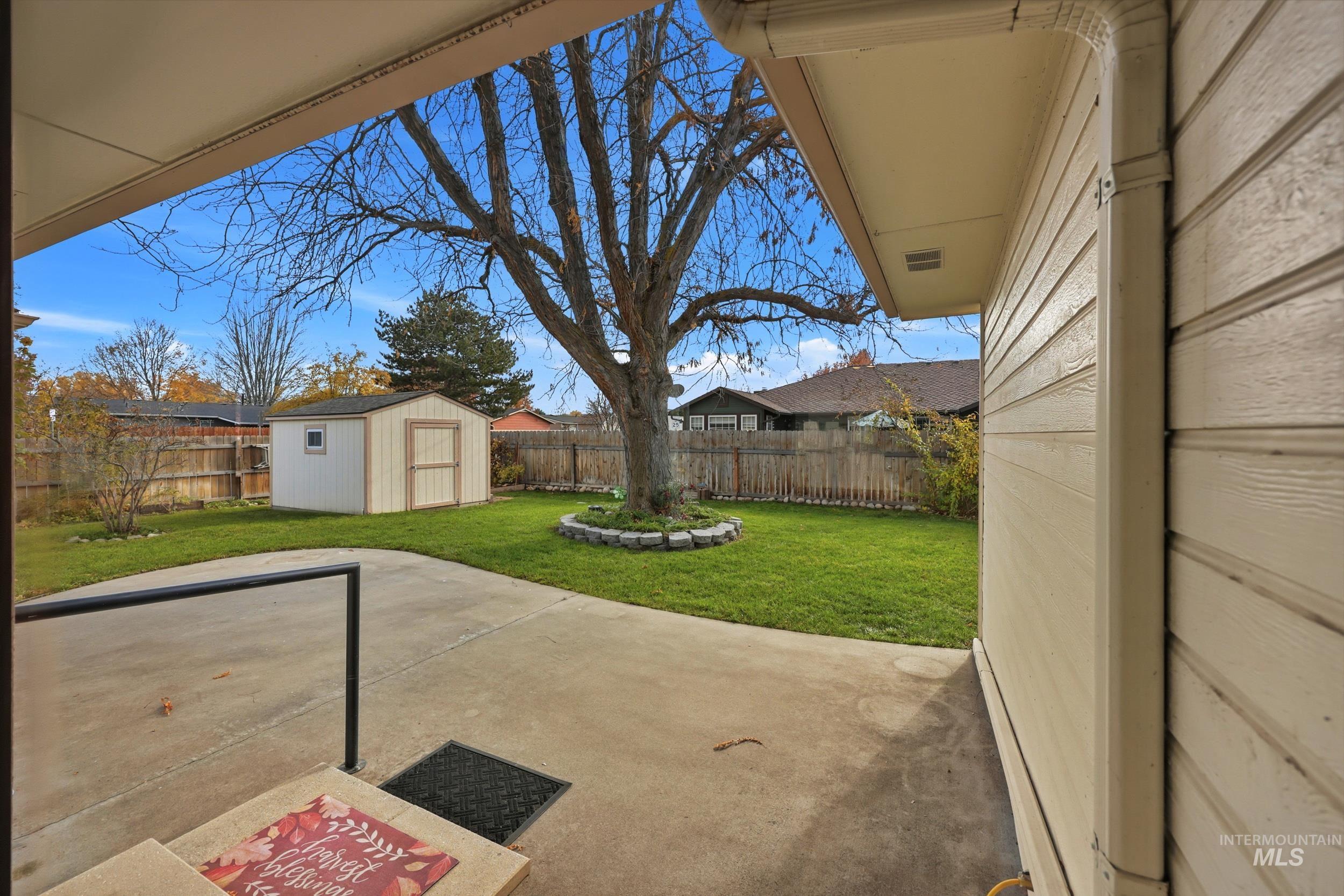 Fenced backyard with a patio and a storage unit