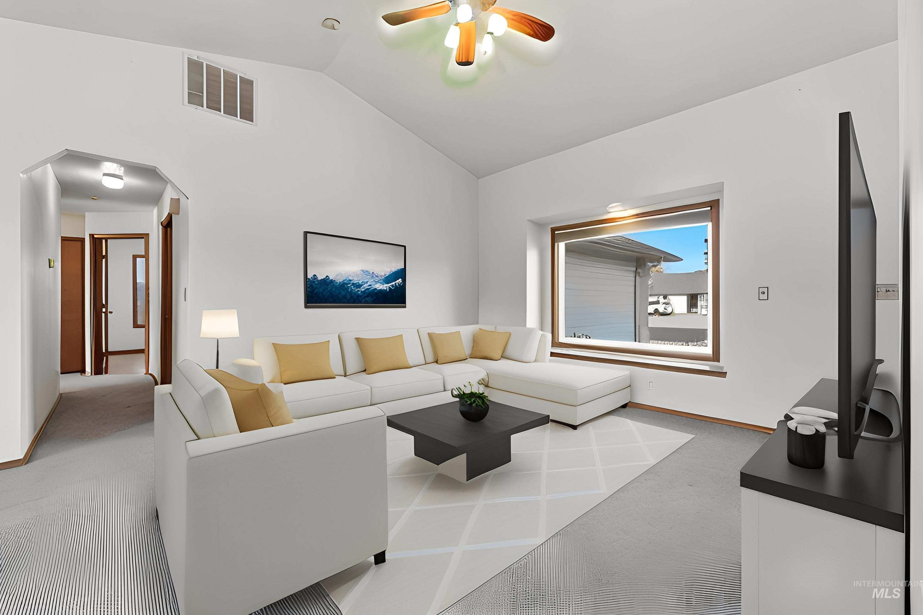 Carpeted living area featuring arched walkways, lofted ceiling, and a ceiling fan