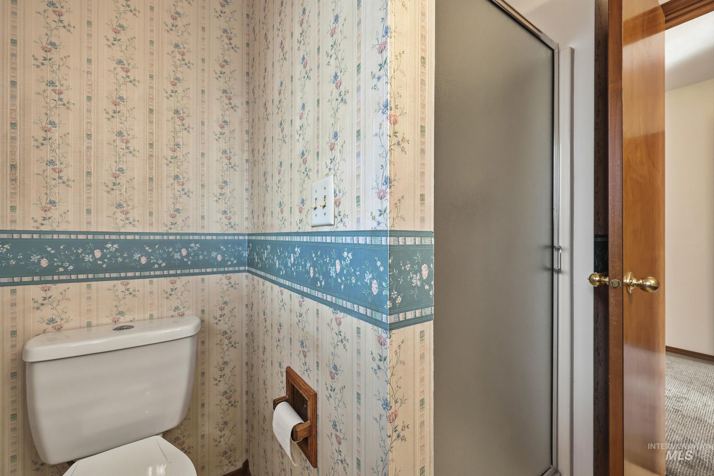 Full bath with a shower stall and wallpapered walls