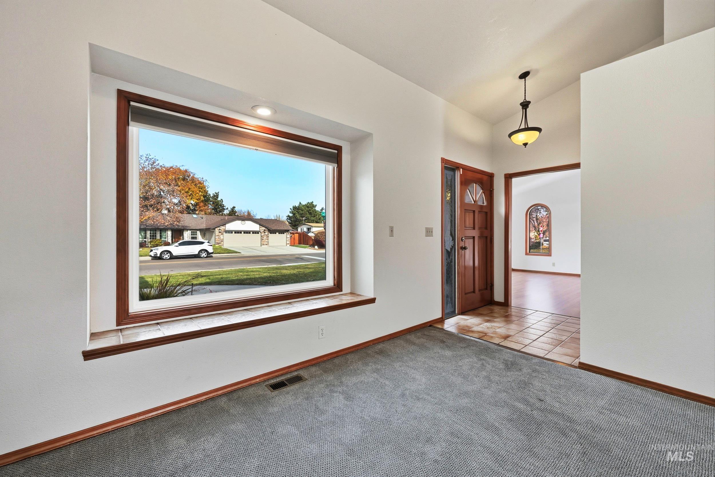 Carpeted foyer featuring lofted ceiling and tile patterned flooring