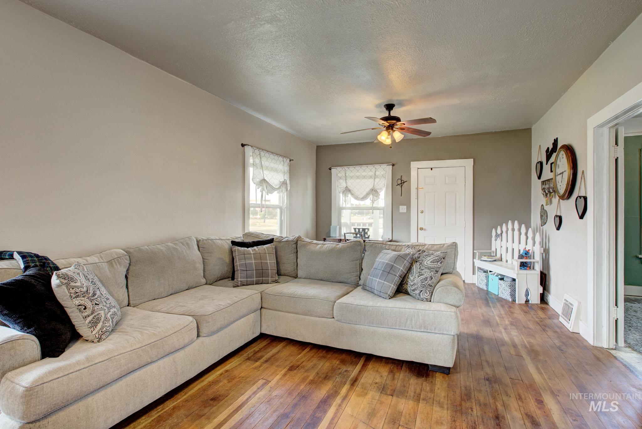 Spacious room featuring wood-finish flooring, light-toned walls, and a ceiling fan with integrated lighting