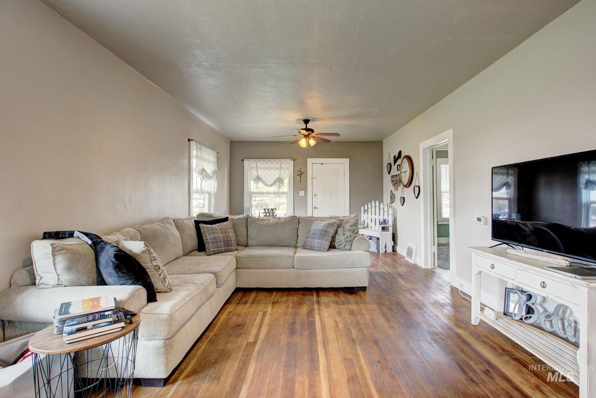 Spacious room featuring wood-finish flooring, light-toned walls, and a ceiling fan with integrated lighting