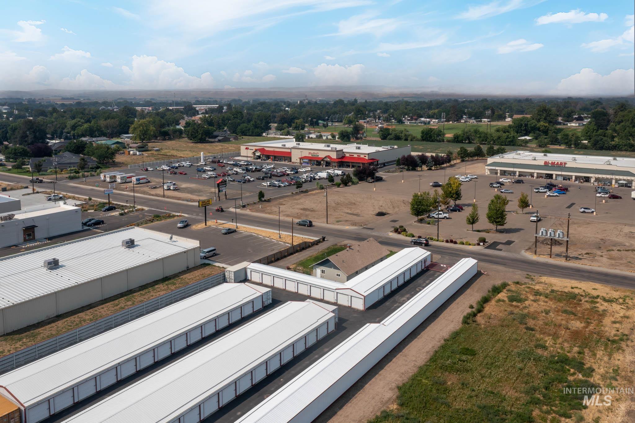 Aerial perspective of commercial properties featuring extensive paved parking areas, multiple retail structures, and self-storage facilities