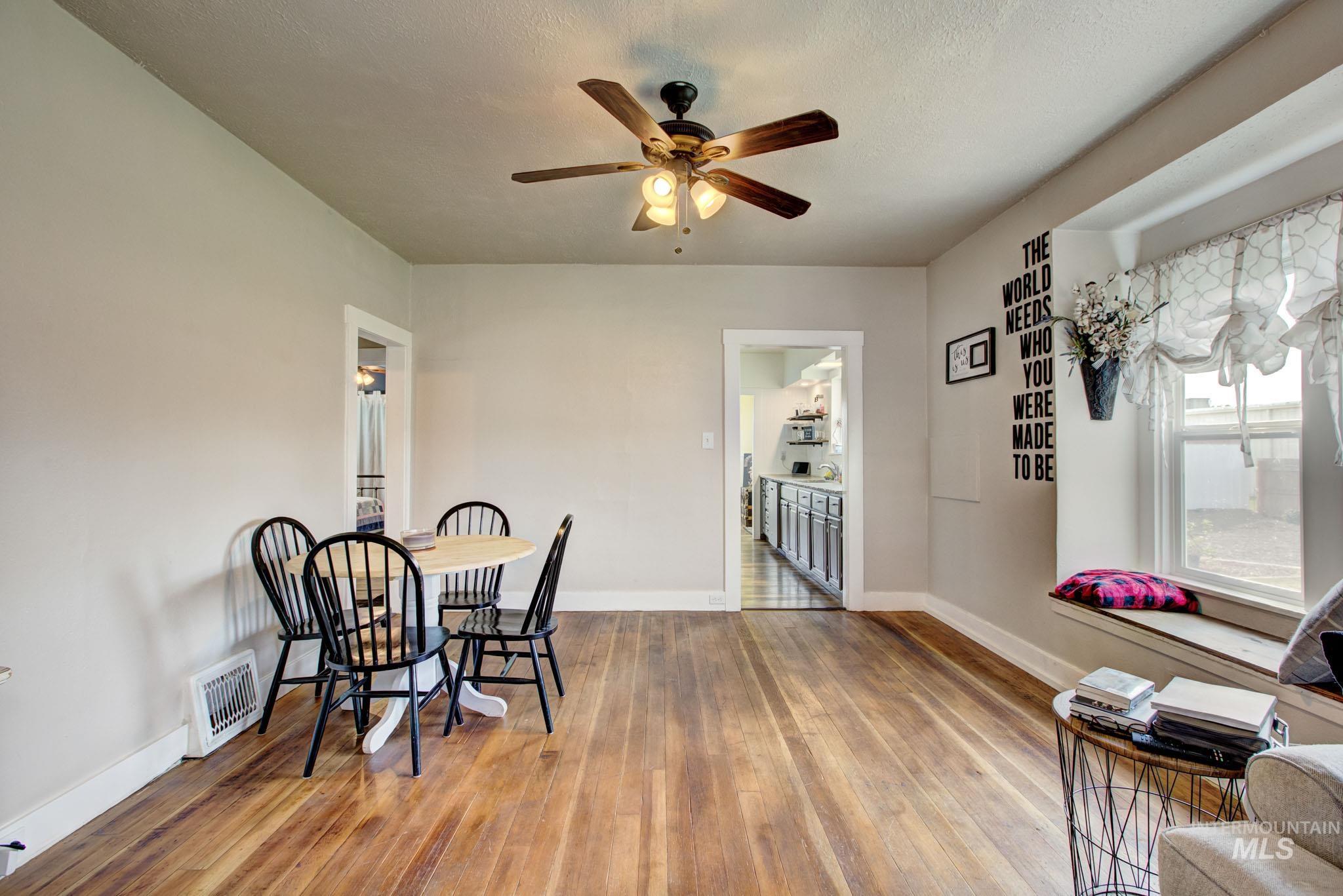 Hardwood-finish flooring throughout, featuring a ceiling fan with integrated lighting and a window with a built-in window seat
