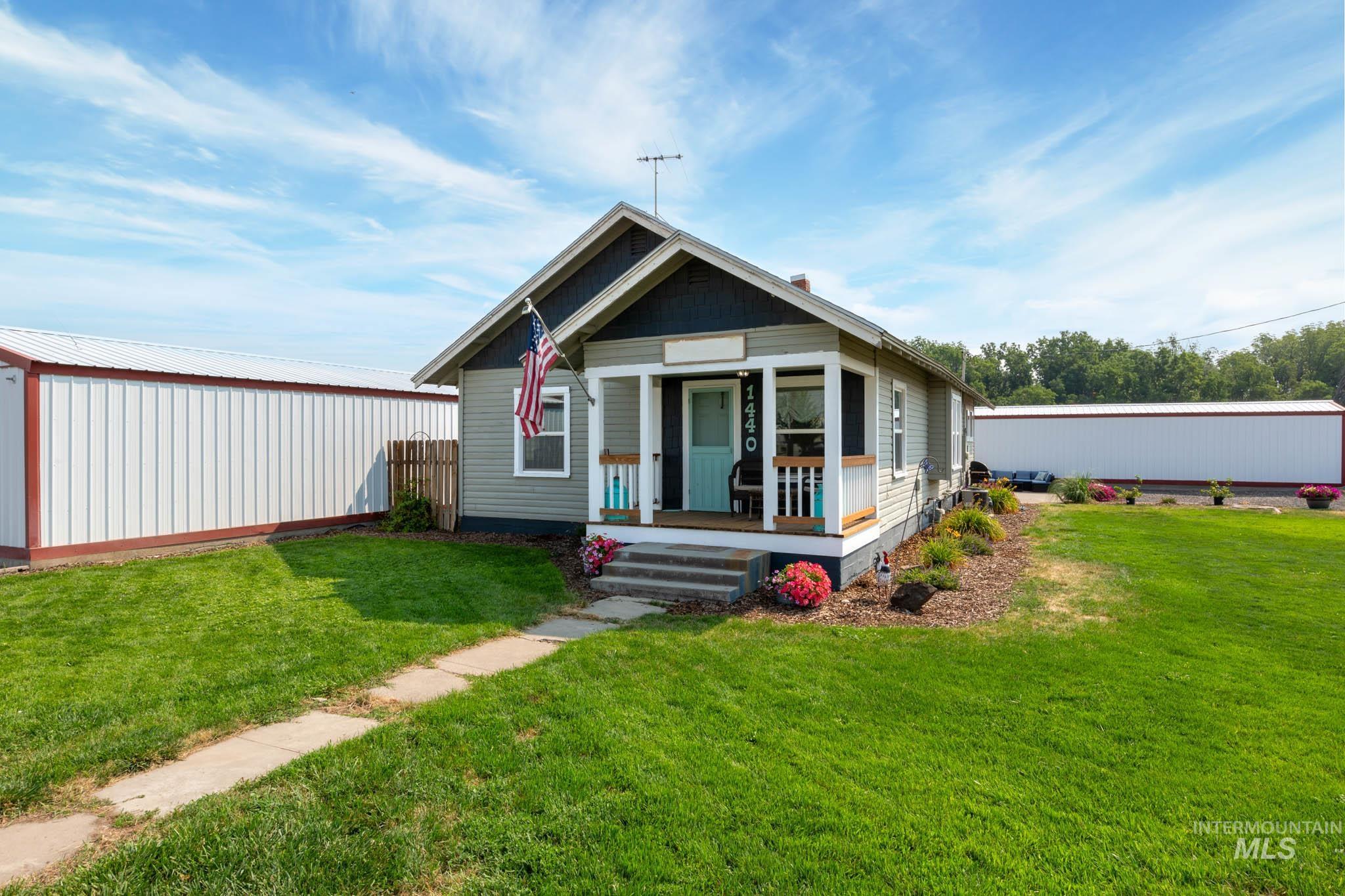Single-story residence featuring a covered front porch, light grey siding, a dark trim roofline, and a concrete walkway