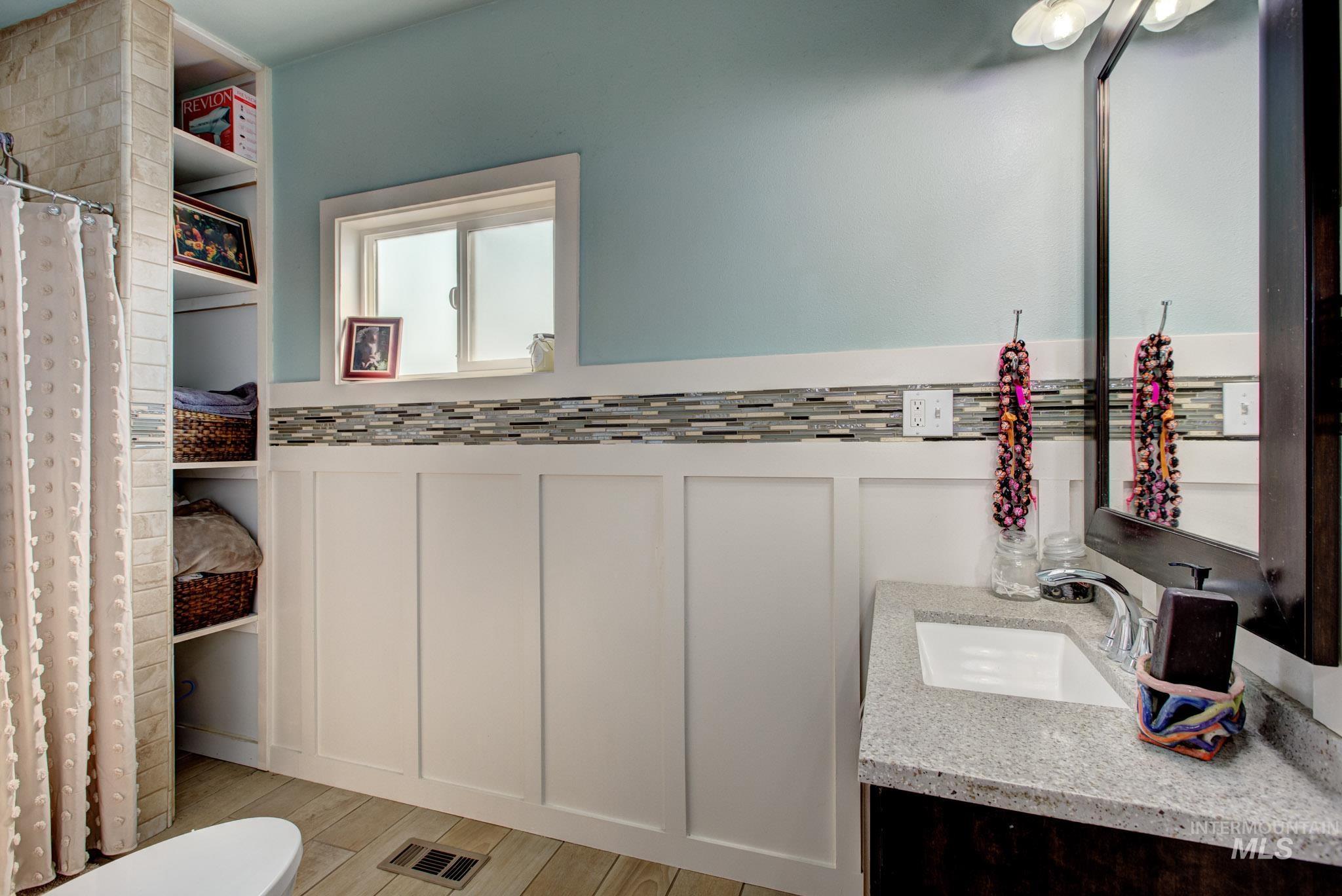Bathroom featuring a single vanity with granite-style countertop, a rectangular undermount sink, and dark wood-finish cabinetry