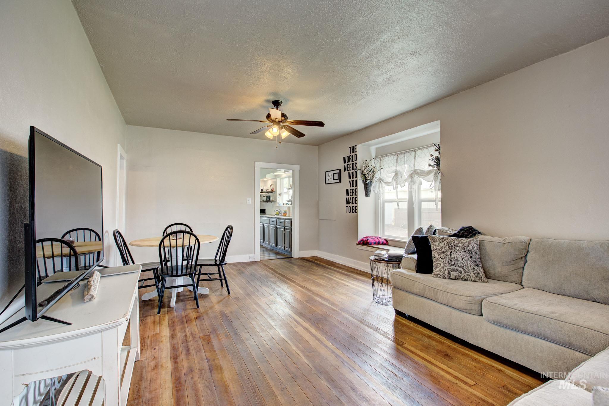 Hardwood flooring spans this room, featuring light gray wall paint and a ceiling fan with integrated lighting