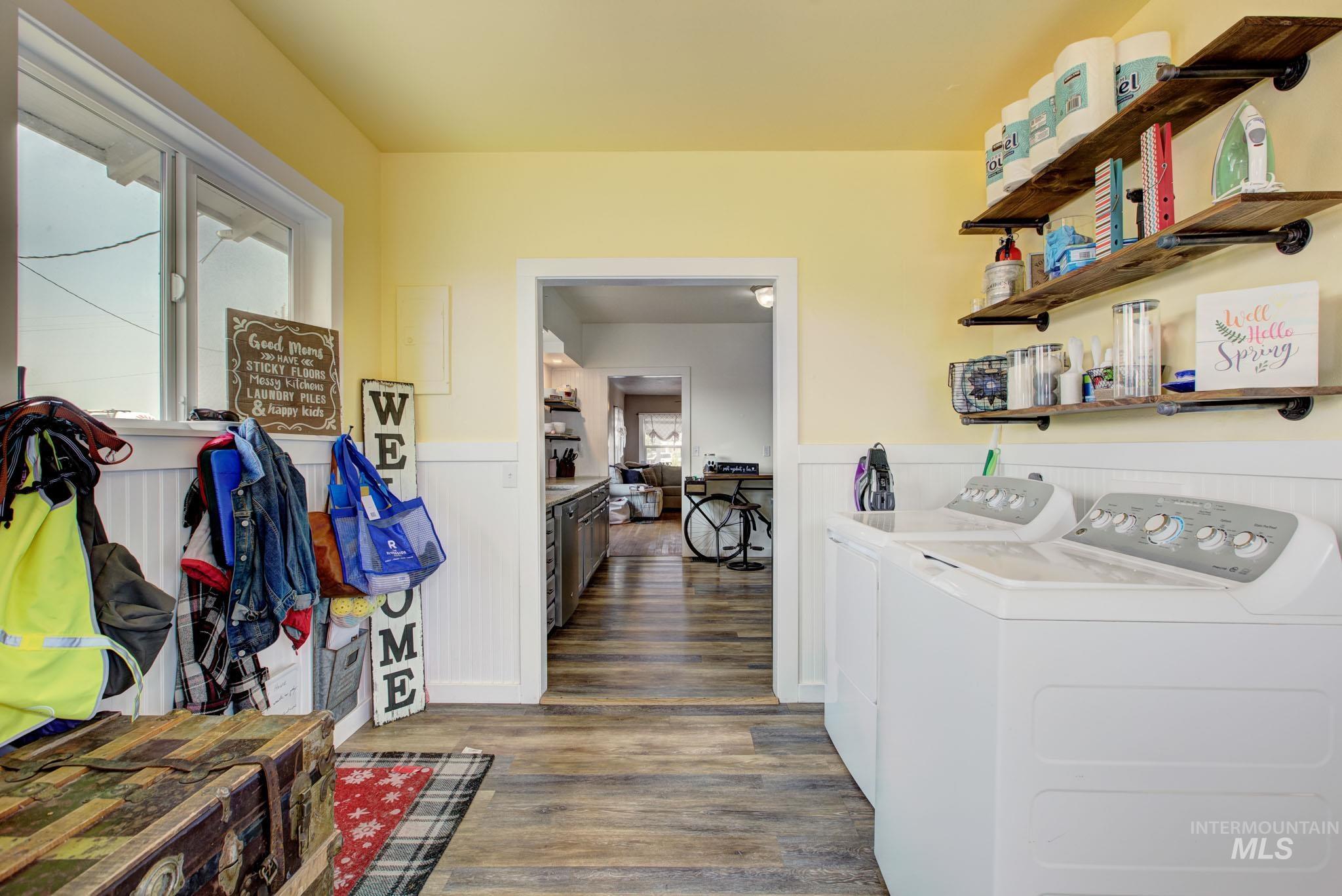 Dedicated laundry room featuring wood-finish flooring, white wainscoting, and a window for natural light