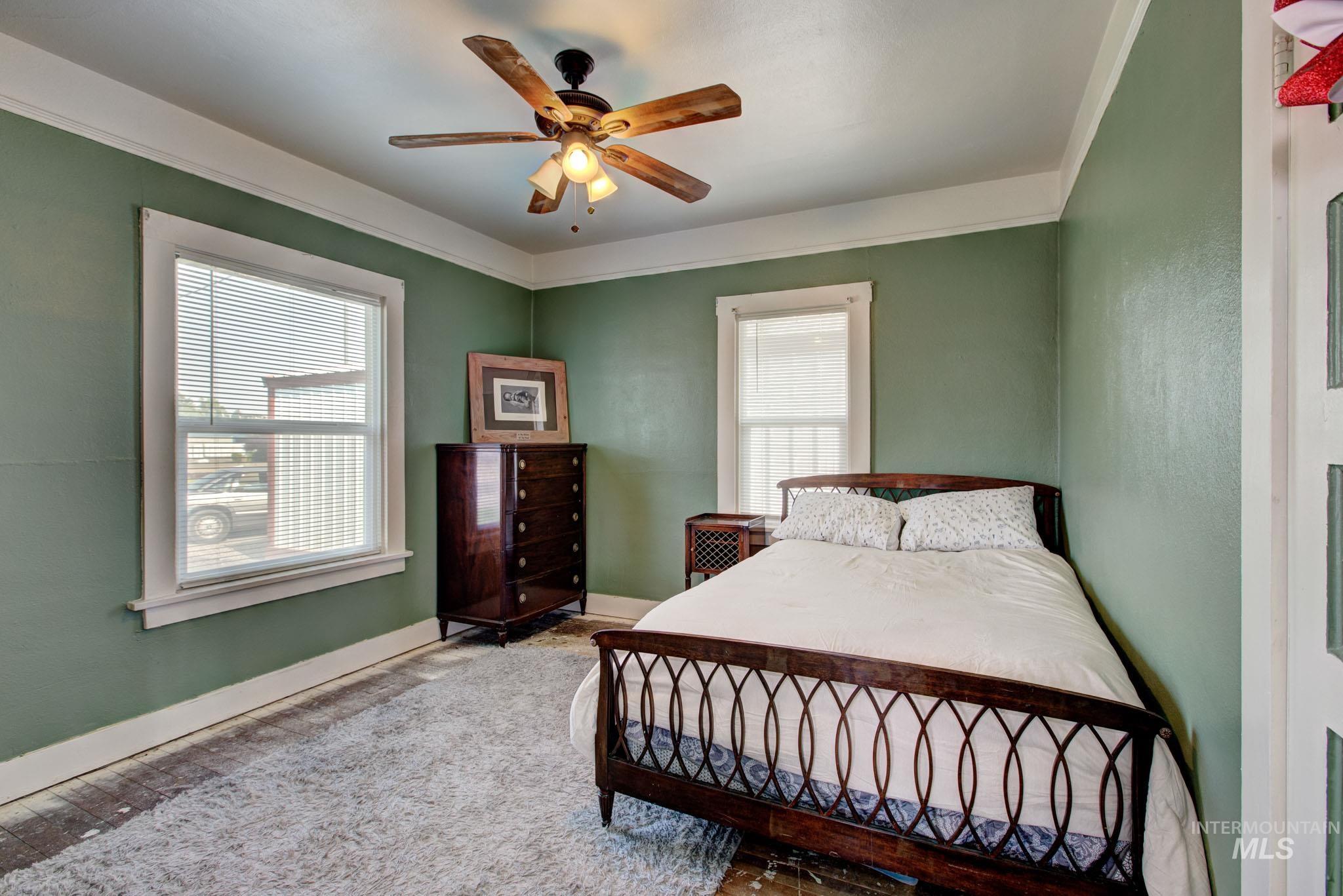 Room with light green walls and white trim, featuring two windows with blinds