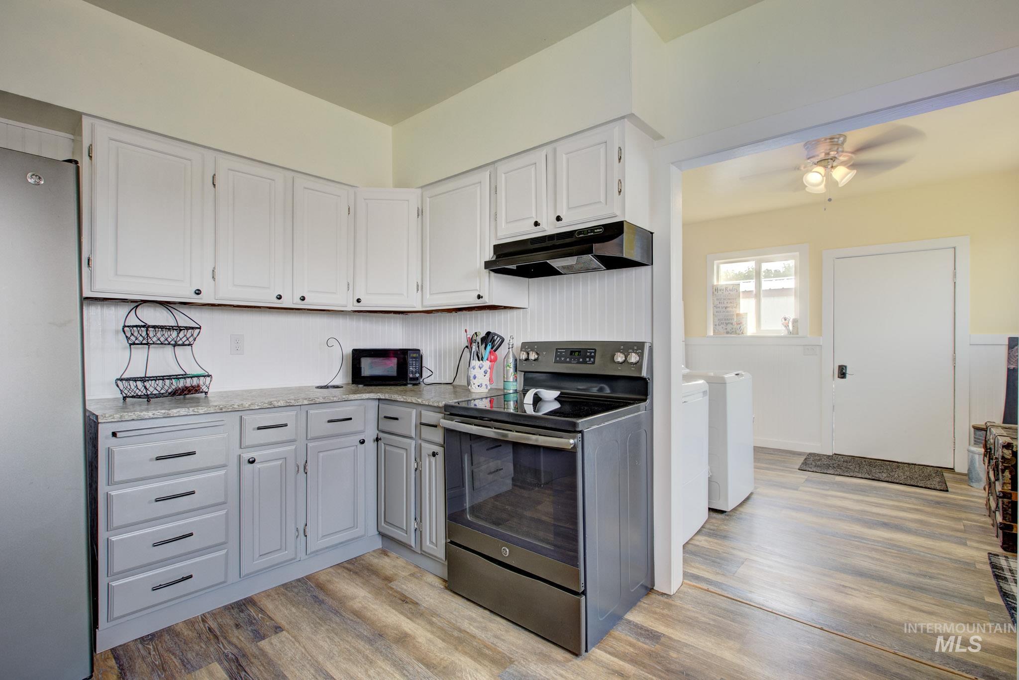 Kitchen featuring two-tone cabinetry with black hardware, granite-look countertops, and wood-finish flooring