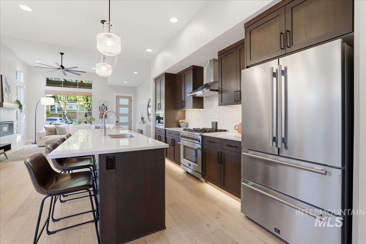 Kitchen featuring premium appliances, open floor plan, dark brown cabinets, tasteful backsplash, and recessed lighting