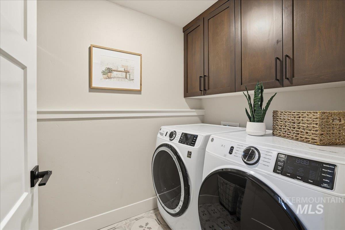 Washroom with cabinet space, washer and dryer, and tile patterned flooring