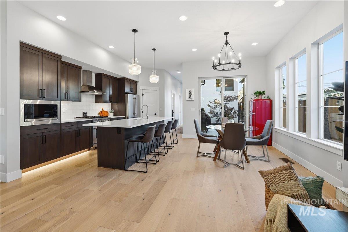 Kitchen featuring a kitchen breakfast bar, decorative light fixtures, recessed lighting, a kitchen island with sink, and appliances with stainless steel finishes