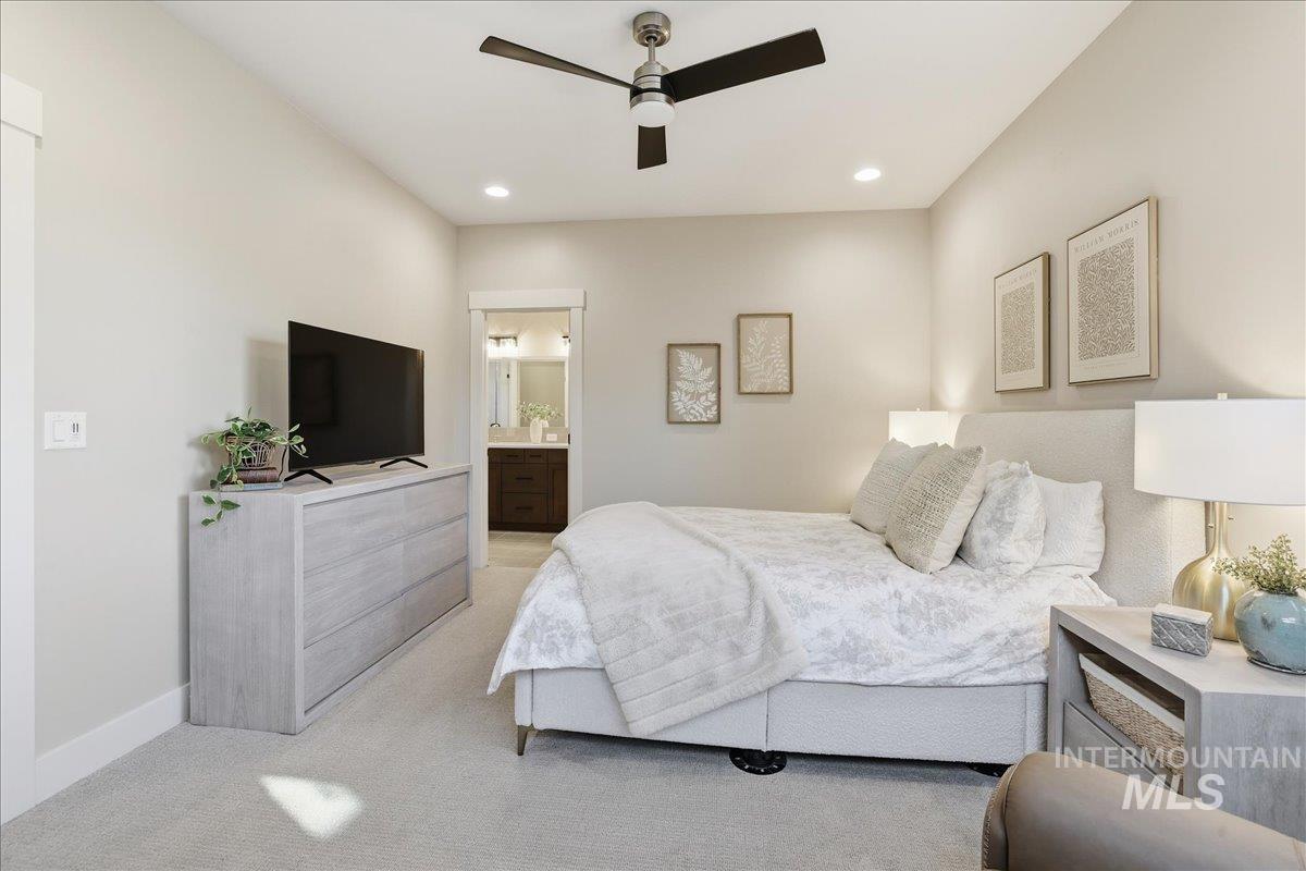 Bedroom with light colored carpet, a ceiling fan, recessed lighting, and ensuite bath