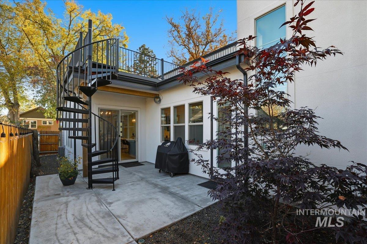 Rear view of property featuring stairs, a patio area, and stucco siding