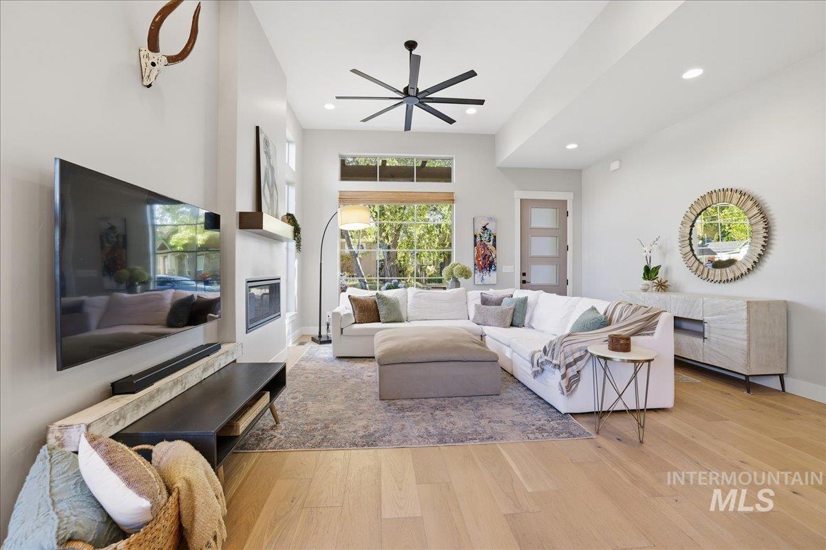Living room featuring recessed lighting, light wood finished floors, a glass covered fireplace, and ceiling fan