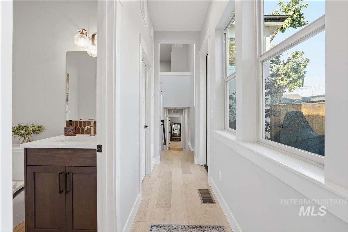 Corridor featuring light wood-type flooring and a sink