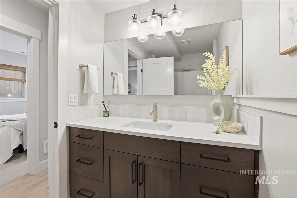 Full bathroom featuring vanity, a shower with shower curtain, light wood finished floors, and connected bathroom