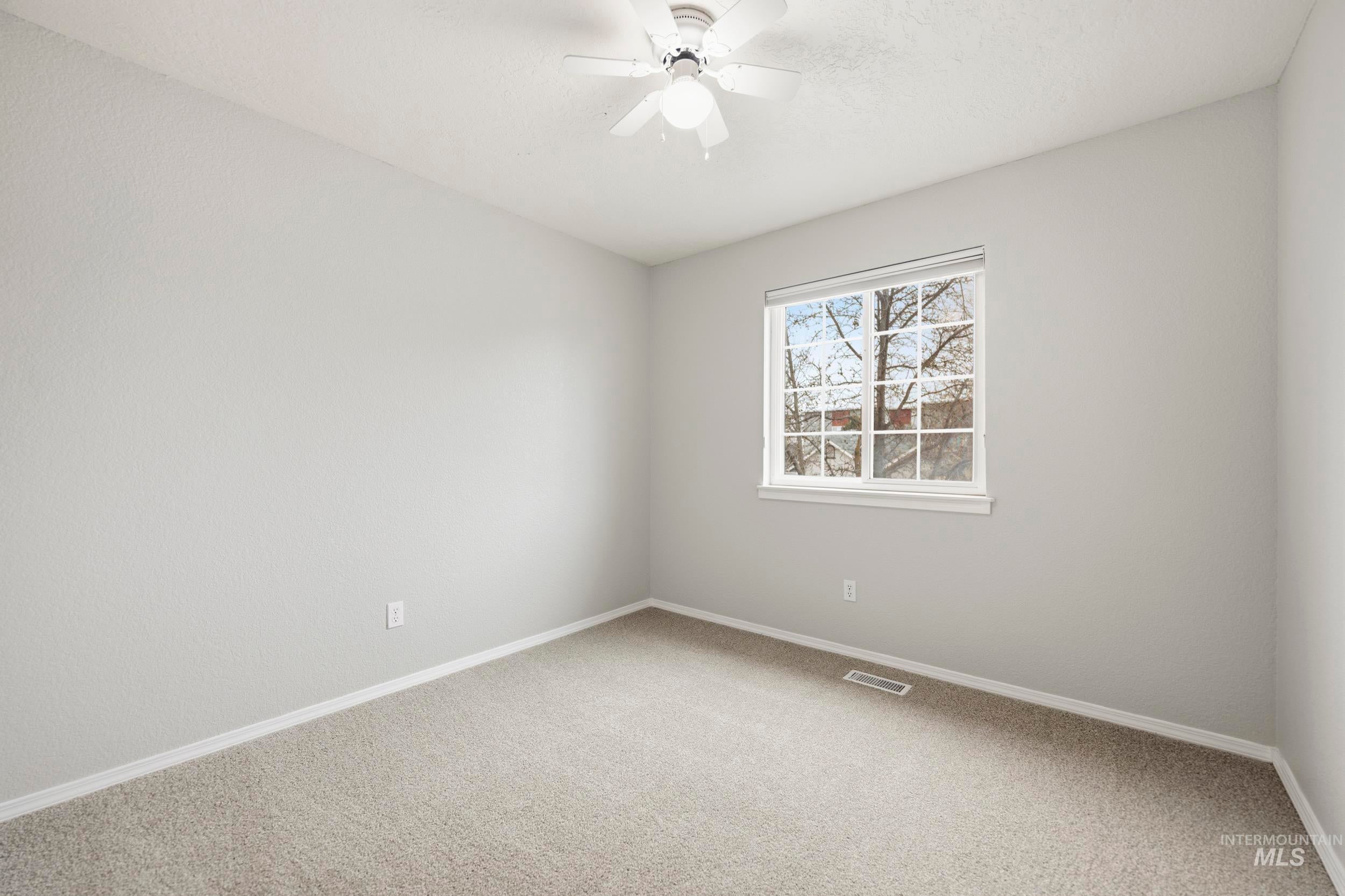 Carpeted spare room featuring baseboards and a ceiling fan